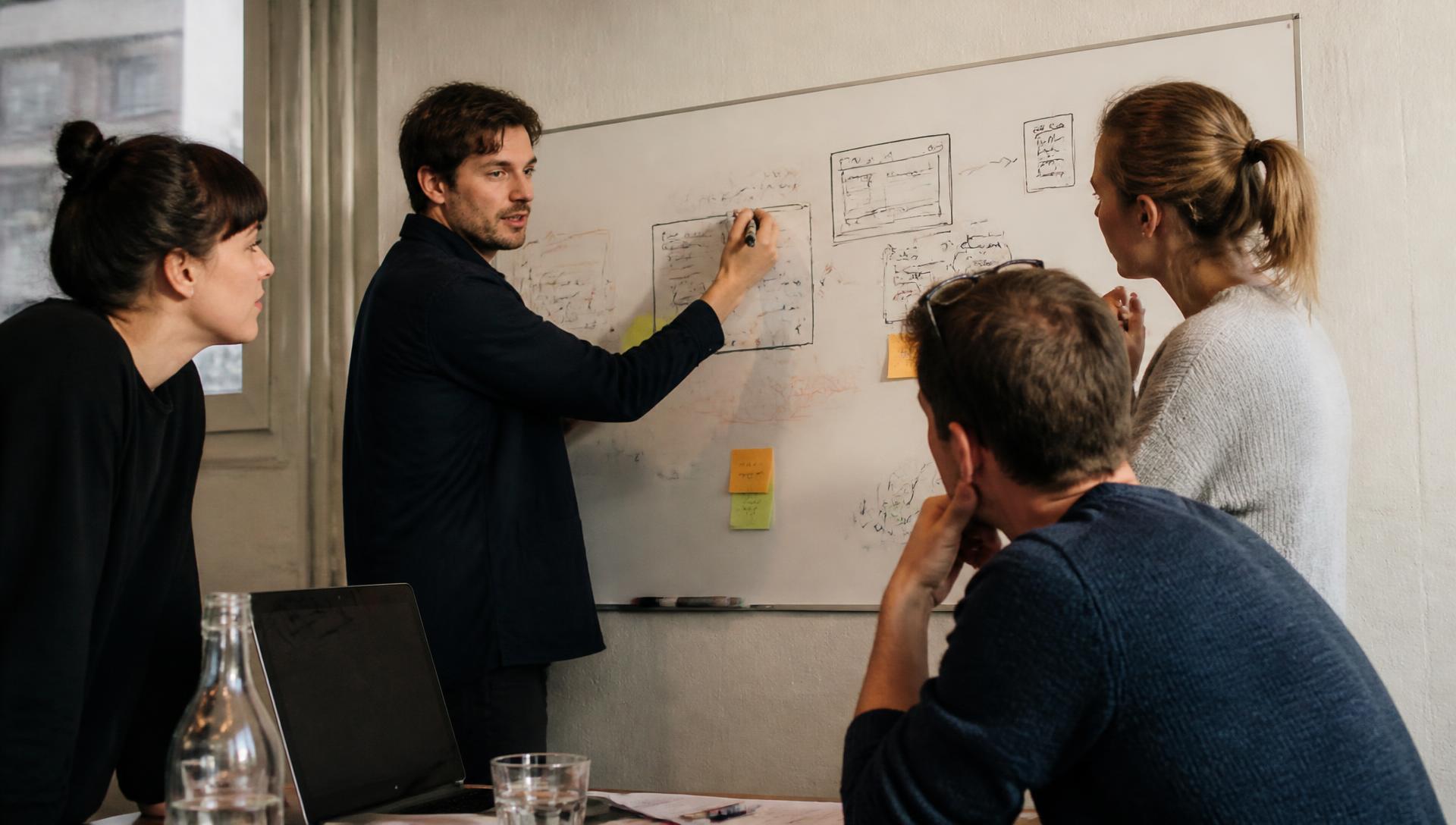 Une équipe discute d’un processus devant un mur d’annotations